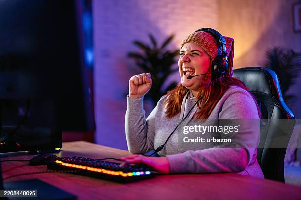 joven ganadora mientras juega un videojuego en su pc de escritorio - videojuego fotografías e imágenes de stock