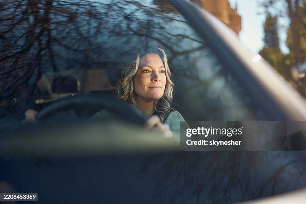 lächelnde frau genießt während der fahrt ein auto. - windschutzscheibe innen stock-fotos und bilder