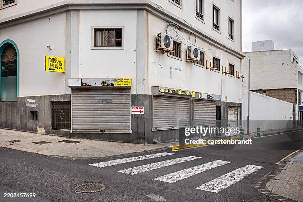 tienda vacía y en bancarrota detrás de una puerta enrollable - bancarrota fotografías e imágenes de stock