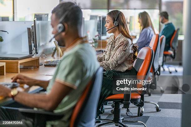 focused mid adult asian businesswoman working at a bright modern office call center - callcenter bildbanksfoton och bilder
