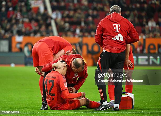 Jamal Musiala of Bayern Munich receives medical treatment during the Bundesliga match between FC Augsburg and FC Bayern München at WWK-Arena on April...