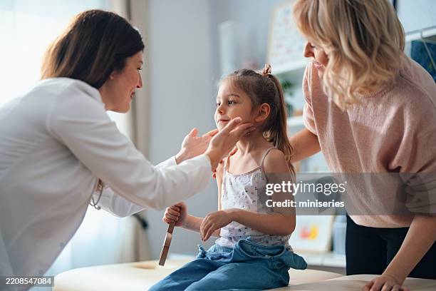 young girl and caring doctor in a pediatric office setting - kinderarts stockfoto's en -beelden