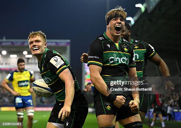 Fin Smith of Northampton Saints celebrates with teammate Henry Pollock after scoring a try during the Investec Champions Cup Round of 16 match...