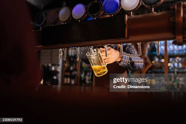 bartender pouring beer from tap in a pub - brewery stock pictures, royalty-free photos & images