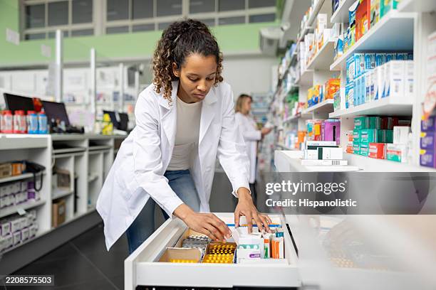 pharmacist searching for medicines at the drugstore - apotheker stockfoto's en -beelden