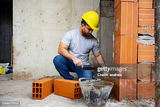 construction worker building a brick wall at a construction site - pedreiro imagens e fotografias de stock
