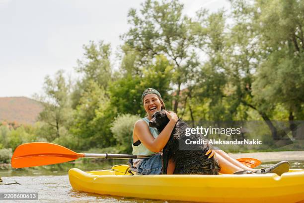 mujer joven navegando en kayak por el río con su amigo peludo - piragüismo fotografías e imágenes de stock