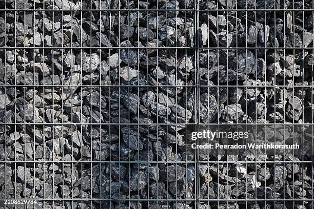 rough gray rocks held together in a structured metal wire grid. - legal defense stock pictures, royalty-free photos & images