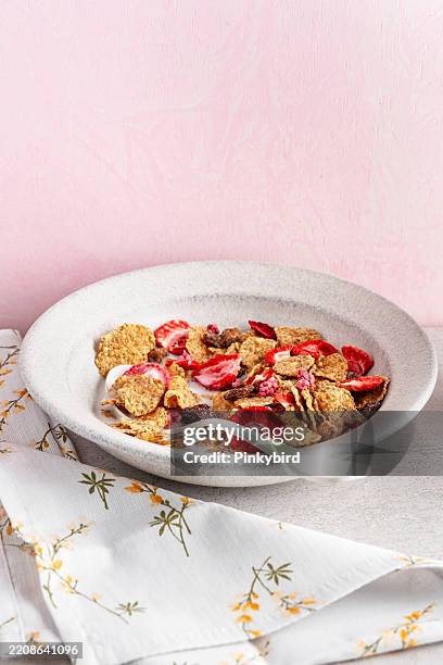 cornflakes cereal and strawberry bowl for breakfast on bowl. dried strawberries and corn flakes. healthy breakfast option: wheat flakes with dried strawberries. whole grain flakes with milk and dried berry fruits. - raisin bran stock pictures, royalty-free photos & images