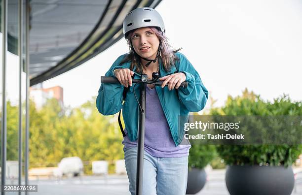 donna che guida il suo e-scooter sul marciapiede in città - veicolo elettrico automobile con biodiesel foto e immagini stock