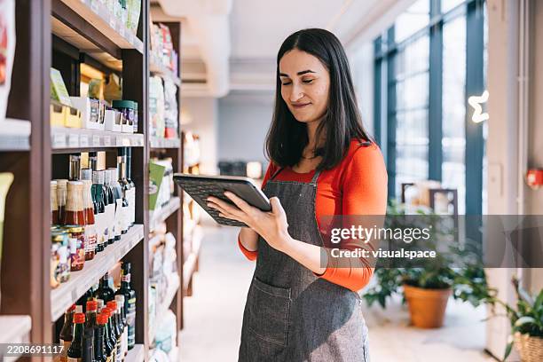 une employée de magasin utilise une tablette numérique pour vérifier les stocks dans le magasin - employé de magasin photos et images de collection