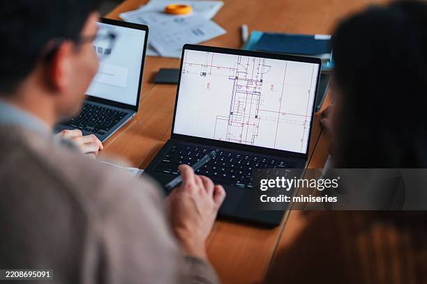 architectural team collaborating on project over digital blueprints in modern workspace - engineering schematic stock pictures, royalty-free photos & images