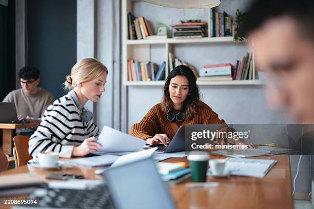 studierende, die in einem gemütlichen bibliothekscafé zusammenarbeiten - warmes licht stock-fotos und bilder
