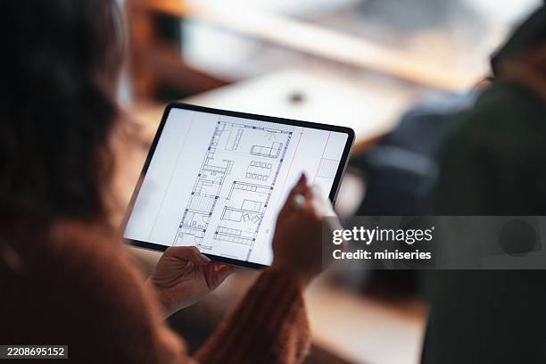 student viewing floor plan on tablet in coffee shop setting - plattegrond stockfoto's en -beelden