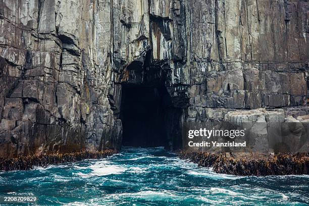 sea cave entrance, rocky wall turquoise water, boat view - grotte stock-fotos und bilder