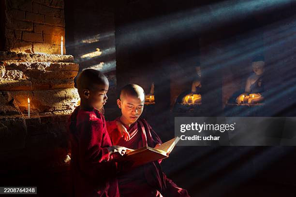 young buddhist monks pray at temple in myanmar - boeddhisme stockfoto's en -beelden