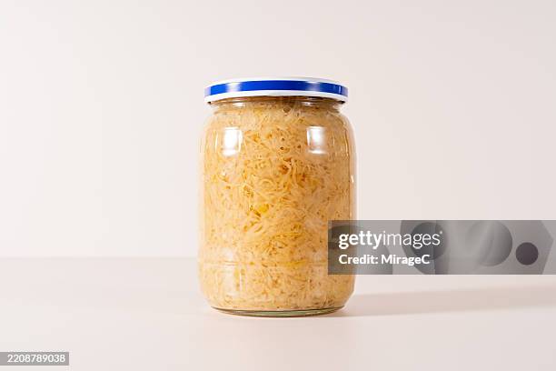 preserved fermented sauerkraut in glass jar on beige background - sauerkraut stock pictures, royalty-free photos & images