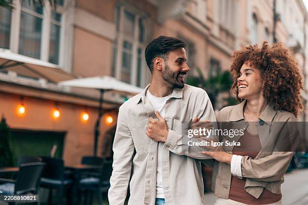 happy couple walking together in the city center - arm in arm stock pictures, royalty-free photos & images