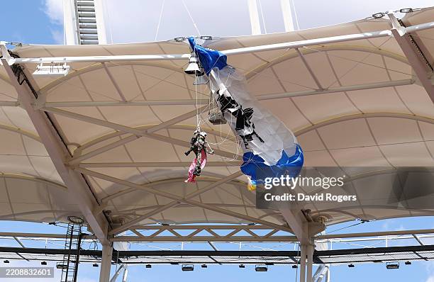 Parachutist delivering the match ball hangs after his parachute line was caught on the roof of the stadium during landing prior to the Investec...