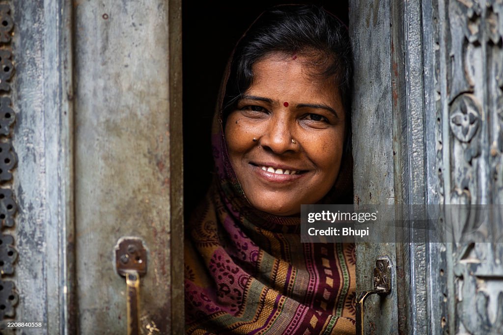Traditional indian woman standing doorway and smiling to the camera.