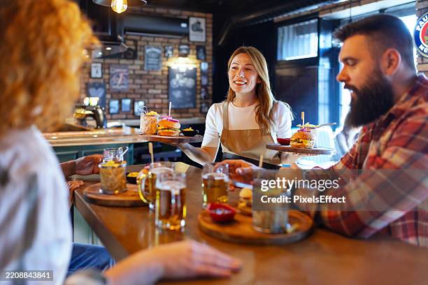 pub perfection: attentive server delivers tasty burgers & fries to happy diners - pub food stock pictures, royalty-free photos & images