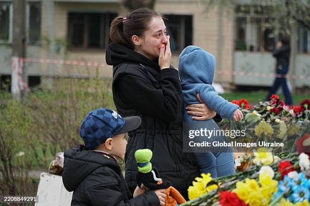 Woman with two children cries near a makeshift memorial on a playground while honoring the memory of a Russian missile strike's victims on April 6,...