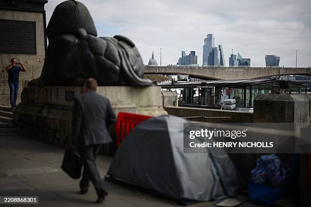 Person walks past a tent alongside Embankment backdropped by the City of London financial district, in London on April 10, 2025.