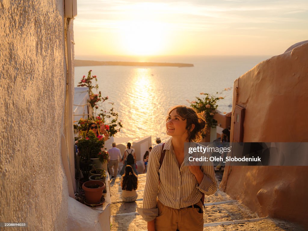 Woman walking on streets on Santorini island at sunset