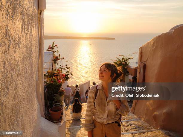 woman walking on streets on santorini island at sunset - turist bildbanksfoton och bilder