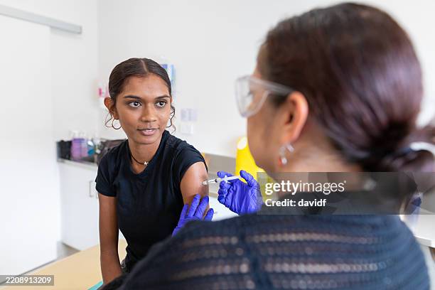 australian aboriginal woman receiving a vaccination injection from an indigenous doctor - vaccination centre stock pictures, royalty-free photos & images