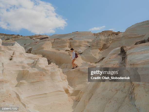 woman exploring white cliffs on sarakiniko beach in greece - sarakiniko beach stock pictures, royalty-free photos & images