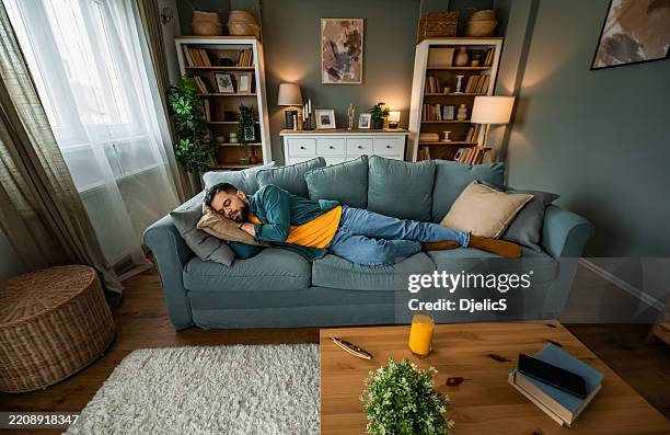 man sleeping at home on sofa. - laziness stock pictures, royalty-free photos & images