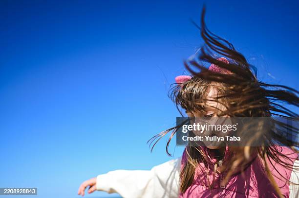 jeune fille jouant et s’amusant à l’extérieur avec les cheveux soufflant au vent - cheveux dans le vent photos et images de collection