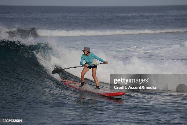 surfer woman paddles sup on big waves - oar stock pictures, royalty-free photos & images