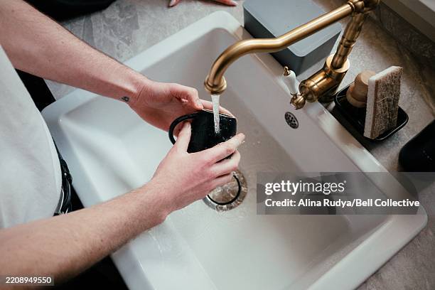 man washing a cup in a kitchen sink - kitchen sink stock pictures, royalty-free photos & images