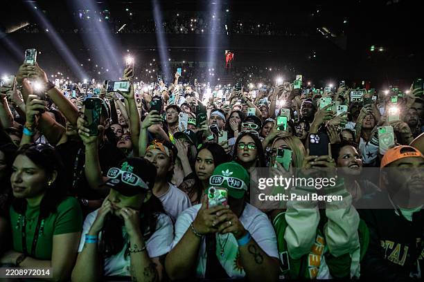 Fans of Columbian singer and singer songwriter Feid holding up the flashlights on their phones in the audience at Afas Live on March 9, 2025 in...