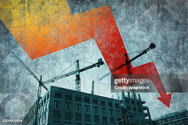 construction site with cranes and downward arrow showing economic decline and industry slowdown - abwertung stock-fotos und bilder