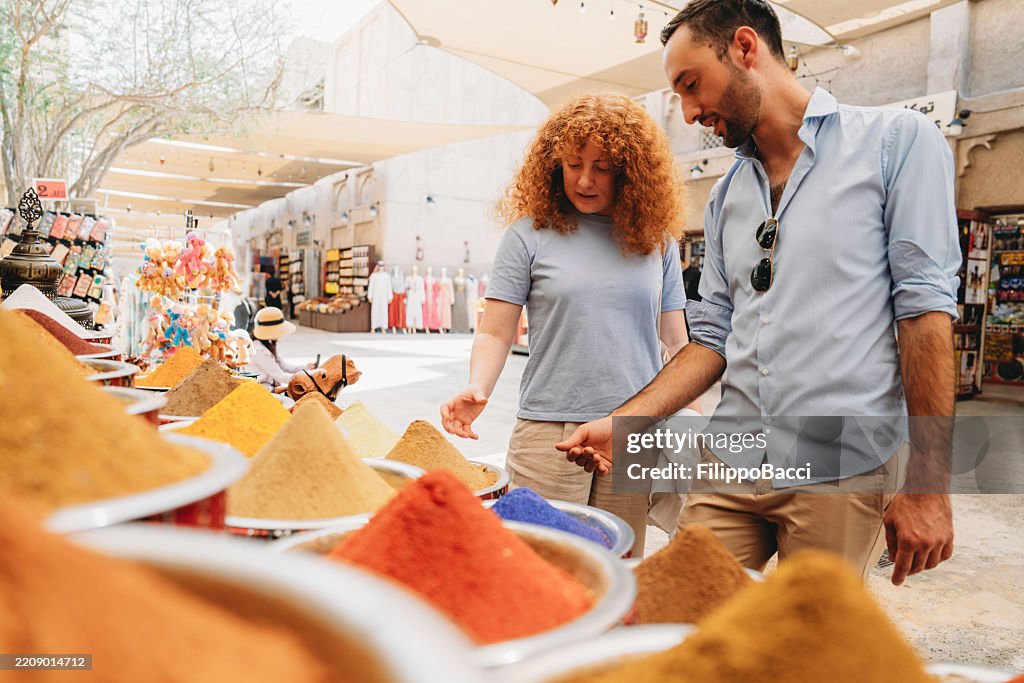 Tourists buying colorful spices at Dubai Spice Souk in Old Dubai