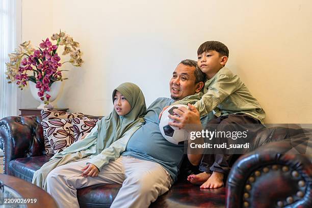 father and kids watching sports on tv - - muslim girl football photos et images de collection
