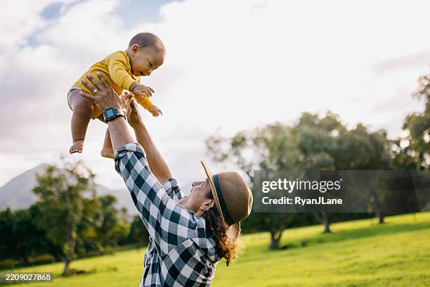 father playfully tossing baby boy into the air - throwing stock pictures, royalty-free photos & images