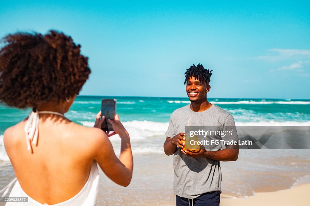 Junge Freundin fotografiert Freund am Strand
