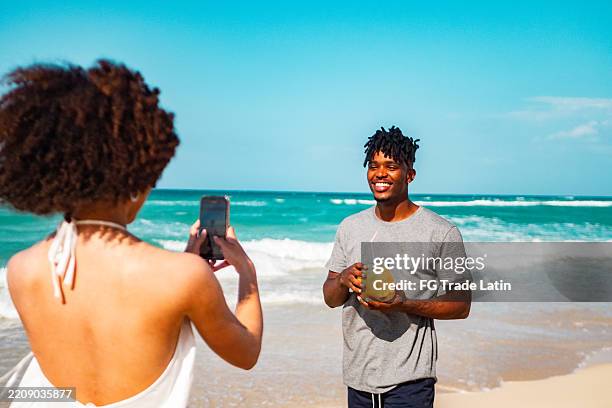 junge freundin fotografiert freund am strand - funkwelle stock-fotos und bilder