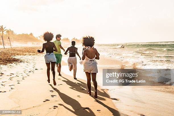 amigos jóvenes felices en la playa - afrocaribeño fotografías e imágenes de stock