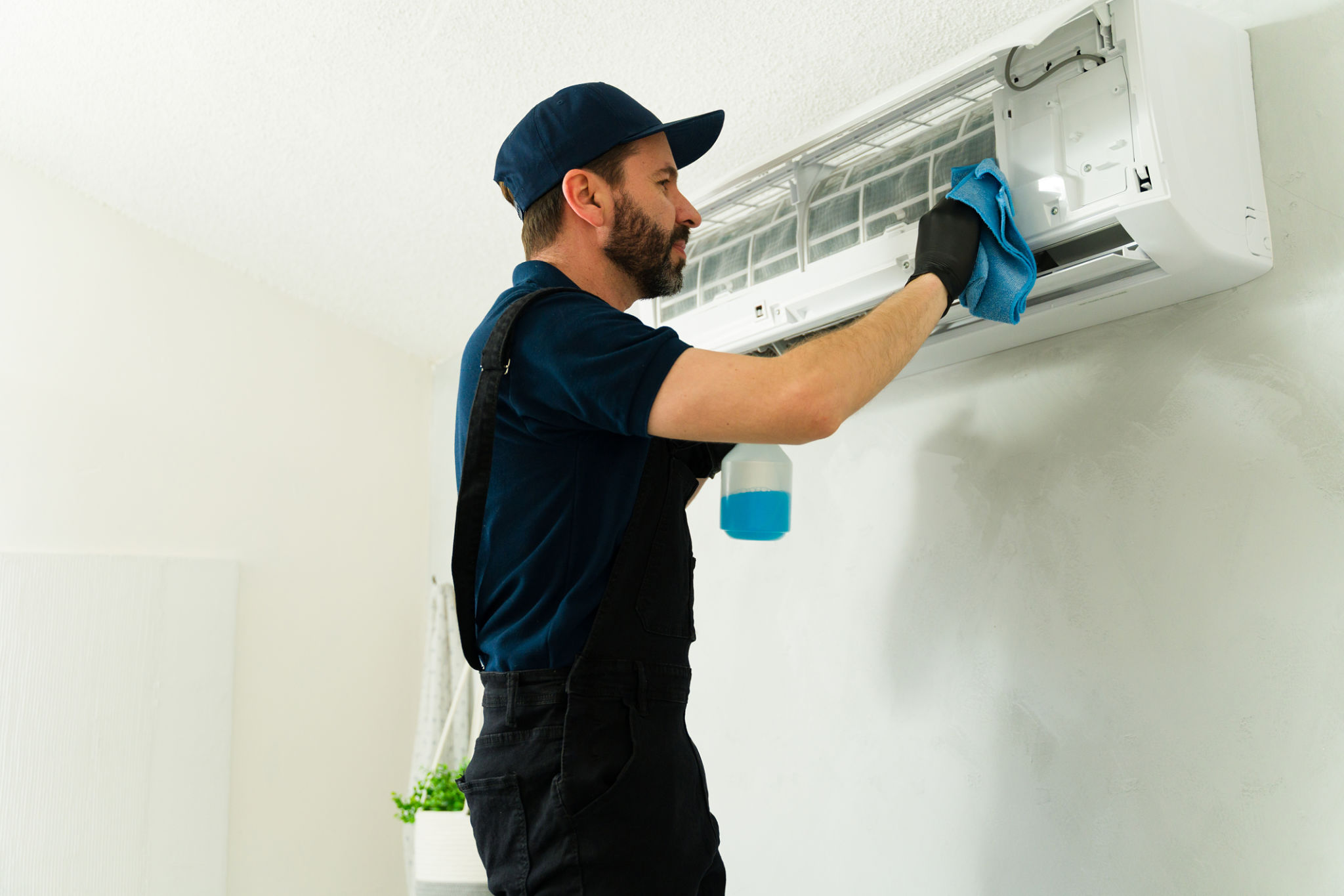 Technician cleaning air conditioner filter with detergent and rag Technician cleaning air conditioner filter with detergent and rag