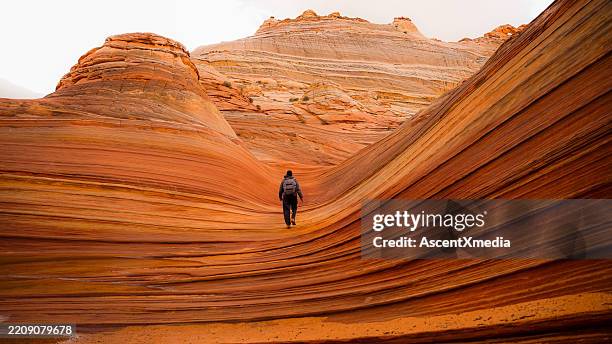 man explores sandstone rock formations - mittlere entfernung stock-fotos und bilder