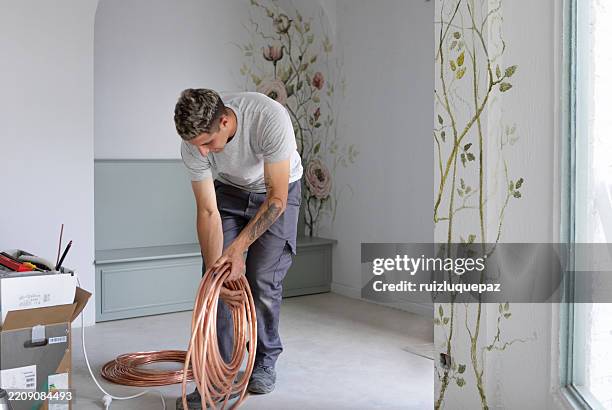 man installing an air conditioner at a renovation project - ductless air conditioner stock pictures, royalty-free photos & images
