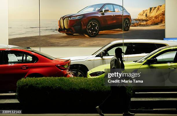 Person walks past BMW cars displayed for sale at a BMW dealership on April 07, 2025 in Glendale, California. The German car maker is being impacted...