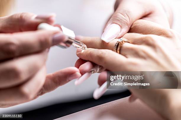 a manicurist applies a nourishing gel to a client's nails. - smalto foto e immagini stock