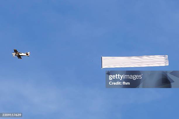 airplane with advertising banner in the sky - banneranzeige stock-fotos und bilder
