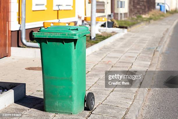 green garbage can on the sidewalk in a residential area - skip bin stock pictures, royalty-free photos & images